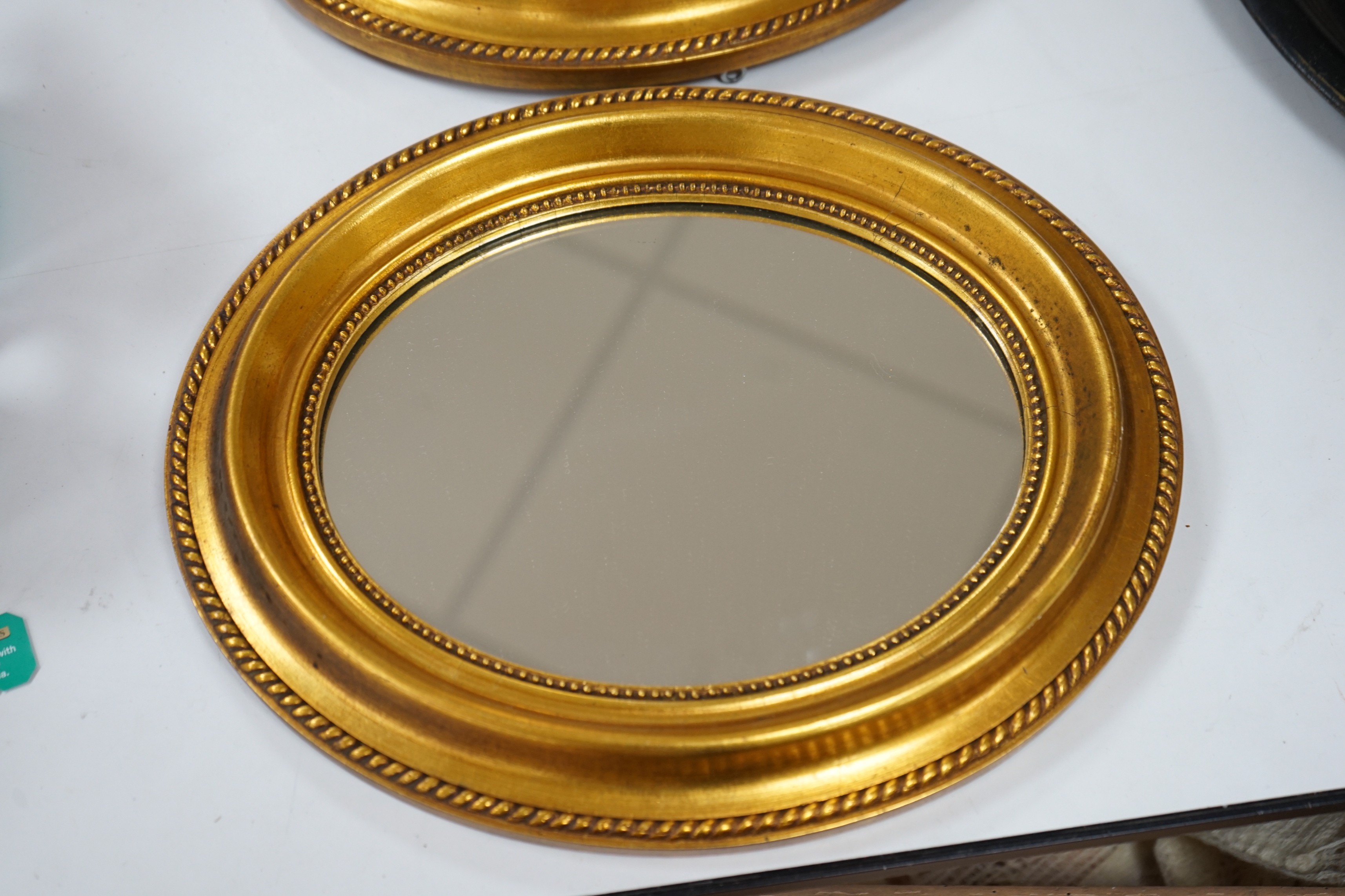 A small pair of oval gilt plaster framed wall mirrors, 34x30cm